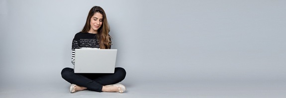 eine Frau sitzend mit einem Notebook auf dem Schoß